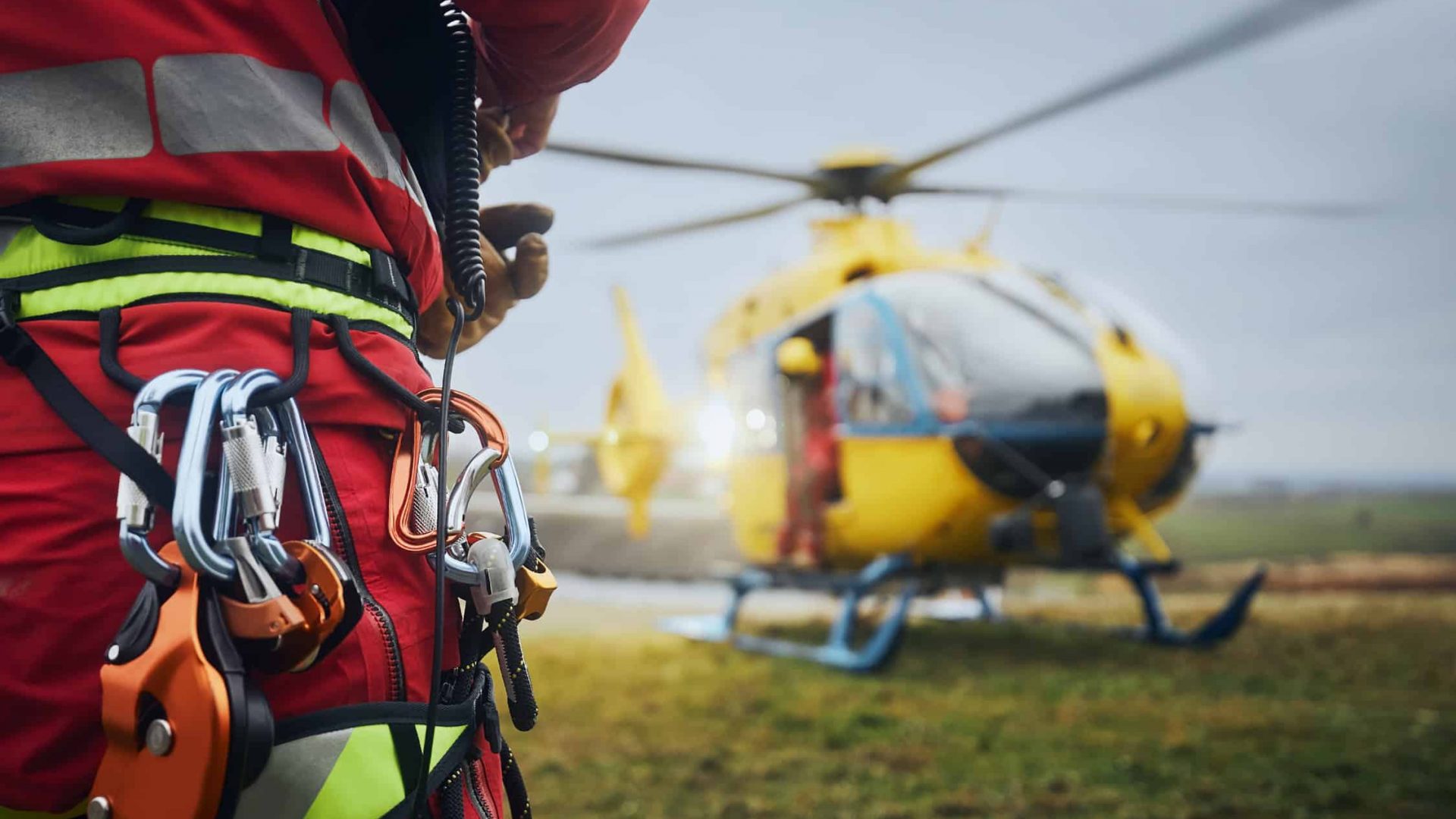 Selective focus on safety harness of paramedic of emergency service in front of helicopter. Themes rescue, help and hope.